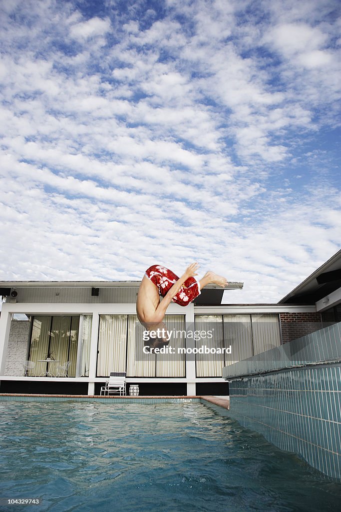 Boy (7-9) jumping into pool, side view