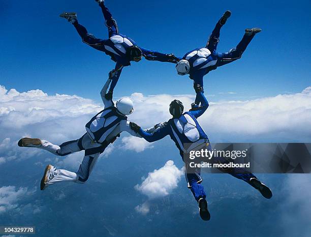 vier unter den skydivern hände halten im ring gegen wolken - fallschirmsprung stock-fotos und bilder