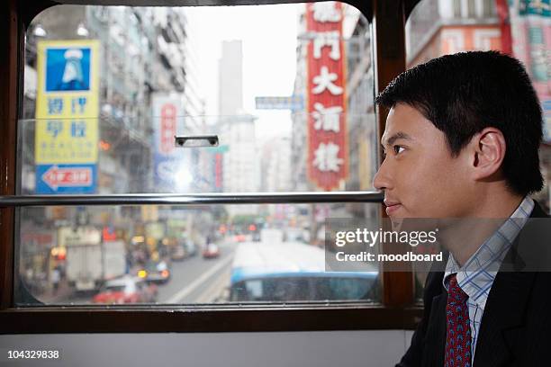 china, hong kong, business man sitting in double decker tram, side view - bus side view stock pictures, royalty-free photos & images