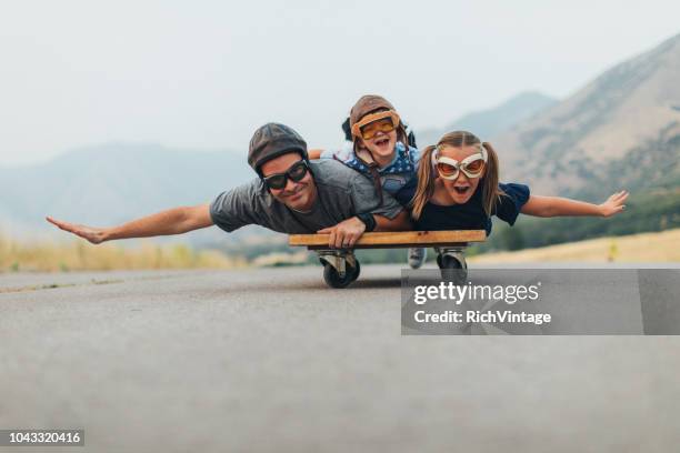 young kids and dad flying on a press cart - adult imagination stock pictures, royalty-free photos & images