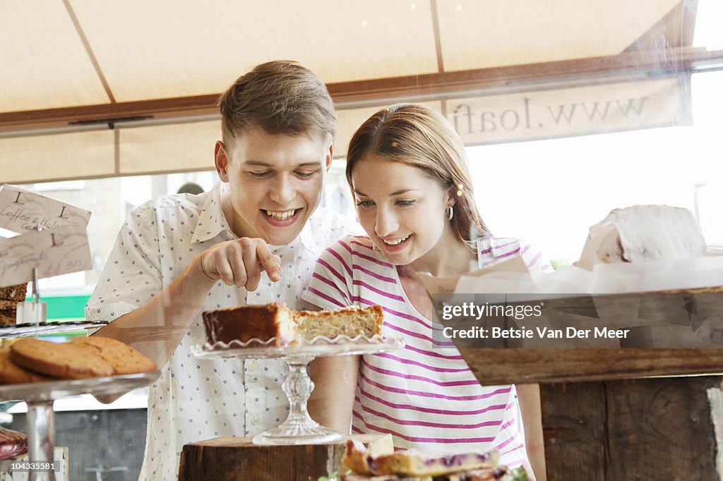 Couple choosing cake in cakeshop window.