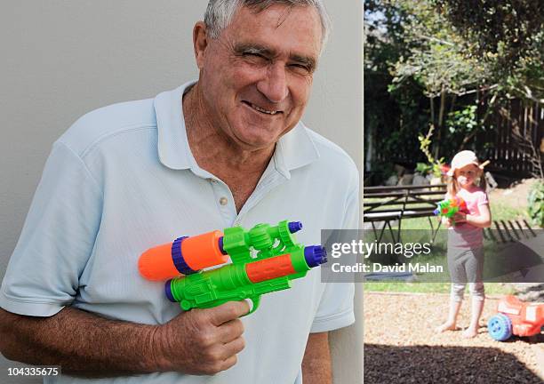 elderly man hiding with a water pistol. - water pistol stock pictures, royalty-free photos & images