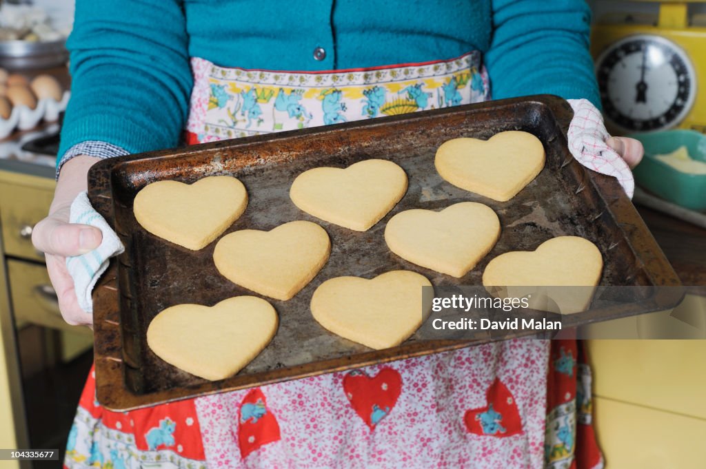 Woman holding a tray of heart shaped cookies