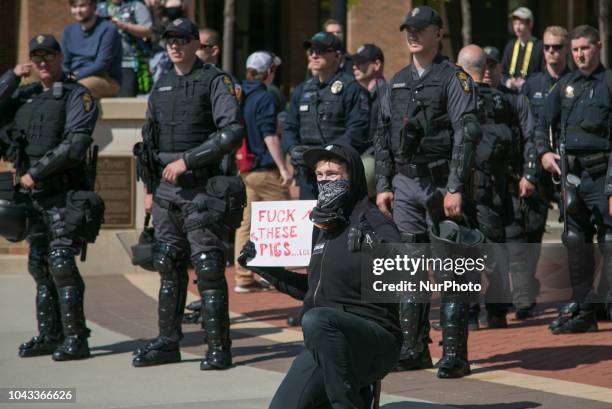 Protester holds a sign in front of police during an open carry rally at Kent State University in Kent, Ohio on September 29, 2018.