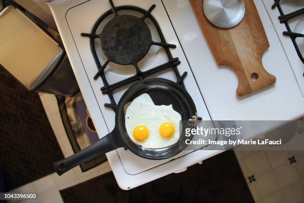 two fried eggs cooking on a stove top - stove top stock-fotos und bilder