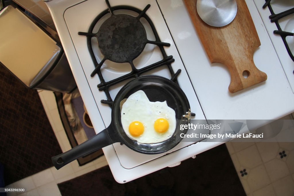 Two fried eggs cooking on a stove top