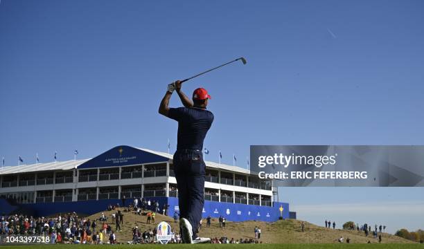 Golfer Tiger Woods plays a tee shot during his singles match with Europe's Spanish golfer Jon Rahm on the third day of the 42nd Ryder Cup at Le Golf...