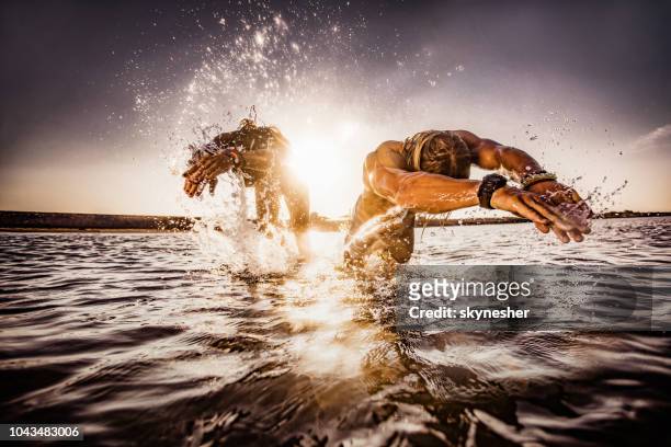 pareja de buceo en el mar al amanecer. - lanzarse al agua salpicar fotografías e imágenes de stock