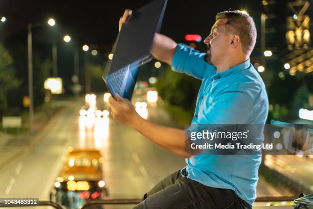 angry man throwing his laptop off a bridge - throwing phone stock pictures, royalty-free photos & images