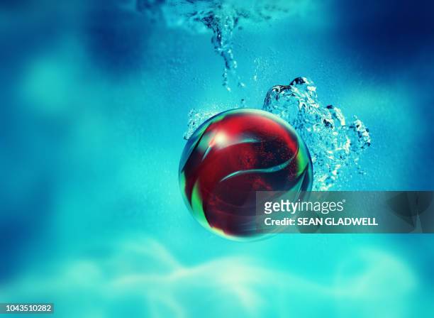 red abstract sphere sinking - balls deep stockfoto's en -beelden