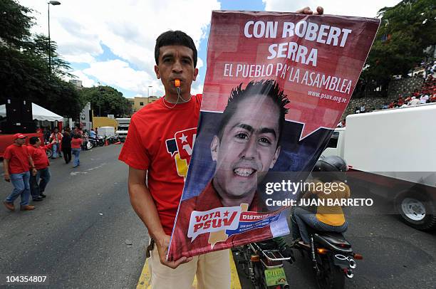 Supporter of Venezuelan President Hugo Chavez holds a poster of Robert Serra, candidate to the Congress, during a rally in view to the upcoming...