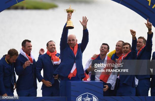 Europe's Danish captain Thomas Bjorn raises the trophy flanked by his team they celebrate winning the 42nd Ryder Cup at Le Golf National Course at...