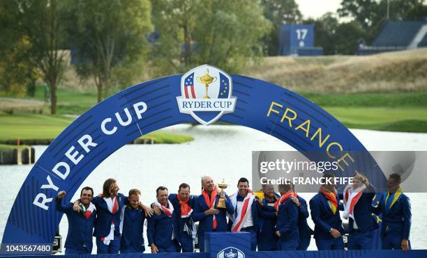 Europe's Danish captain Thomas Bjorn raises the trophy flanked by his team as they celebrate winning the 42nd Ryder Cup at Le Golf National Course at...