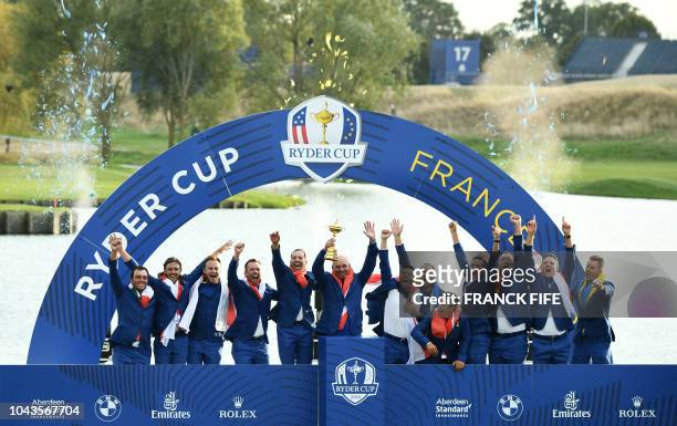 Europe's Danish captain Thomas Bjorn raises the trophy flanked by his team as they celebrate winning the 42nd Ryder Cup at Le Golf National Course at...