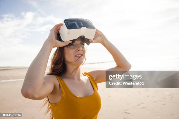 redheaded woman using vr glasses on the beach - virtual vacations stock pictures, royalty-free photos & images