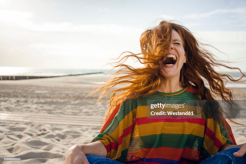 Woman sitting on the beach, screaming for joy