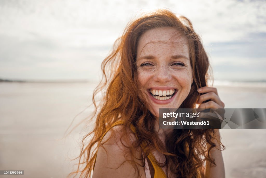 Portrait of a redheaded woman, laughing happily on the beach