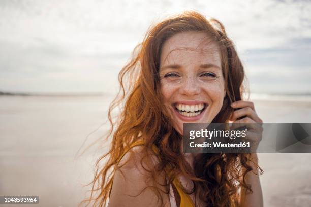 portrait of a redheaded woman, laughing happily on the beach - gioia foto e immagini stock