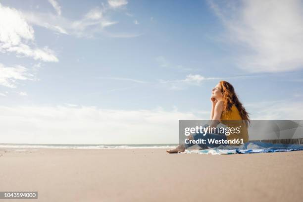 woman sitting on the beach, enjoying the sun - woman towel beach stock-fotos und bilder