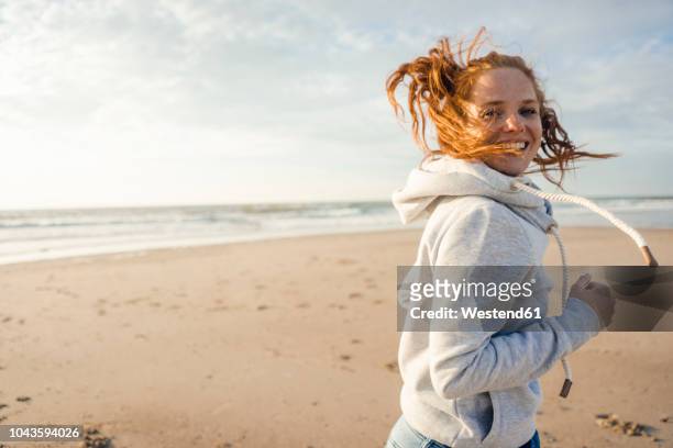 redheaded woman running on the beach, laughing - netherlands beach stock pictures, royalty-free photos & images