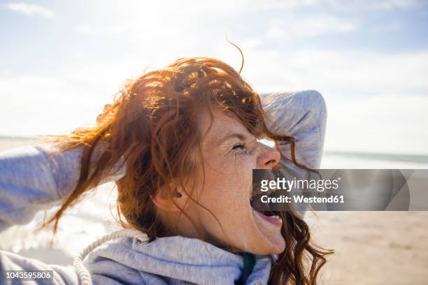 redheaded woman enjoying fresh air at the beach - shouting stock pictures, royalty-free photos & images