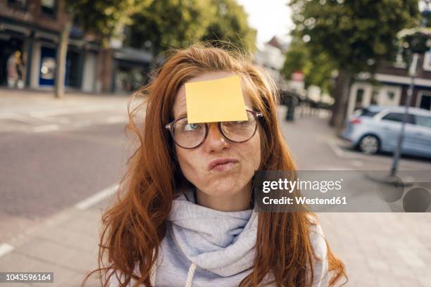 redheaded woman with adhesive note sticking on her forehead - lembrança imagens e fotografias de stock