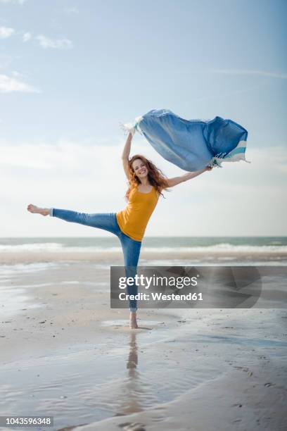 happy woman having fun at the beach, dancing and swaying towel - barefoot redhead ストックフォトと画像