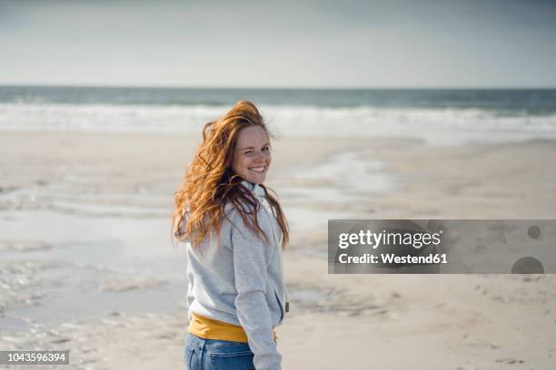 redheaded woman relaxing on the beach, laughing - zwinkern stock-fotos und bilder