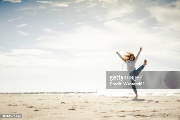 happy woman having fun at the beach, dancing in the sand - training copy space stockfoto's en -beelden
