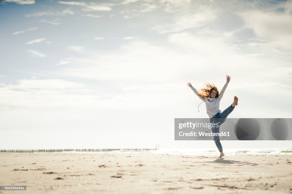 Happy woman having fun at the beach, dancing in the sand