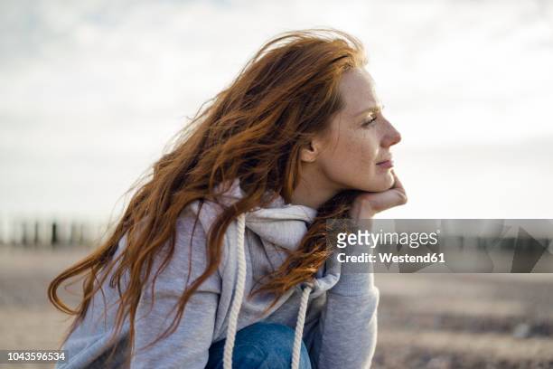 redheaded woman enjoying fresh air at the beach - positieve emotie stockfoto's en -beelden