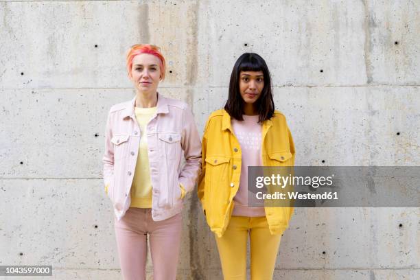 two alternative friends having fun, wearing yellow and pink jeans clothes - nebeneinander-stehen stock-fotos und bilder