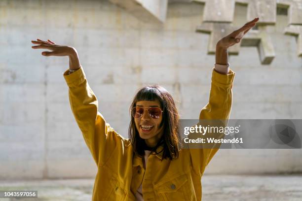 young woman singing, raising arms - fashionable fotografías e imágenes de stock