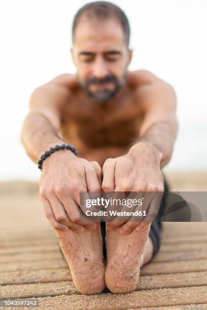 spain. man doing yoga on the beach in the evening, stretching legs, hands and soles of feet - male feet soles 個照片及圖片檔