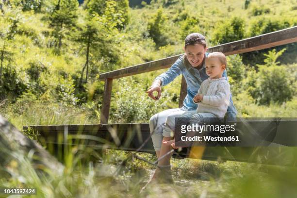 mother and daughter sitting on wooden bridge - baby gender reveal stock pictures, royalty-free photos & images