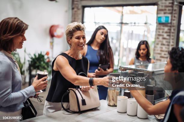 mature woman ordering coffee, while her colleagues are queuing - sydney cup stock pictures, royalty-free photos & images