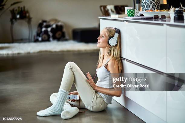 young woman wearing headphones listening to music at home - sitting on ground stock pictures, royalty-free photos & images