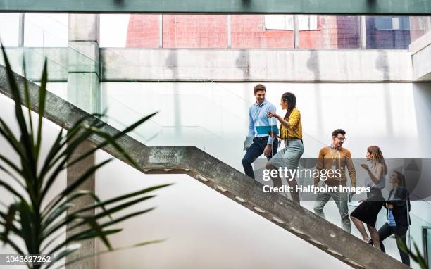 a group of businesspeople walking up the stairs in the modern building, talking. - person walking up stairs stock pictures, royalty-free photos & images