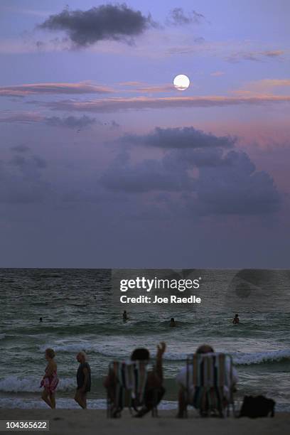 The full moon is seen in the sky over people enjoying the beach on September 22, 2010 in Miami Beach, Florida. Today marks the first time in two...