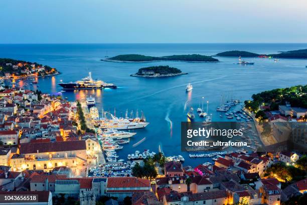 view of the illuminated old town hvar and the harbor with pakleni islands at dusk - hvar croatia stock pictures, royalty-free photos & images