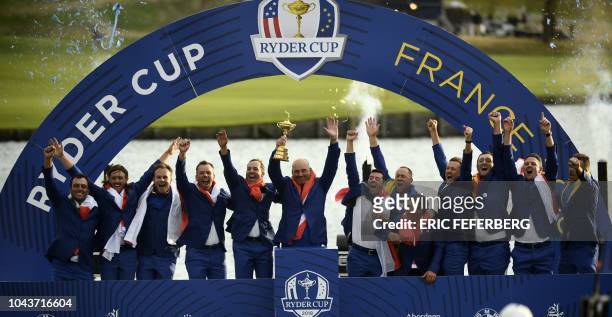 Europe's Danish captain Thomas Bjorn celebrates with his team and the trophy after winning the 42nd Ryder Cup at Le Golf National Course at...