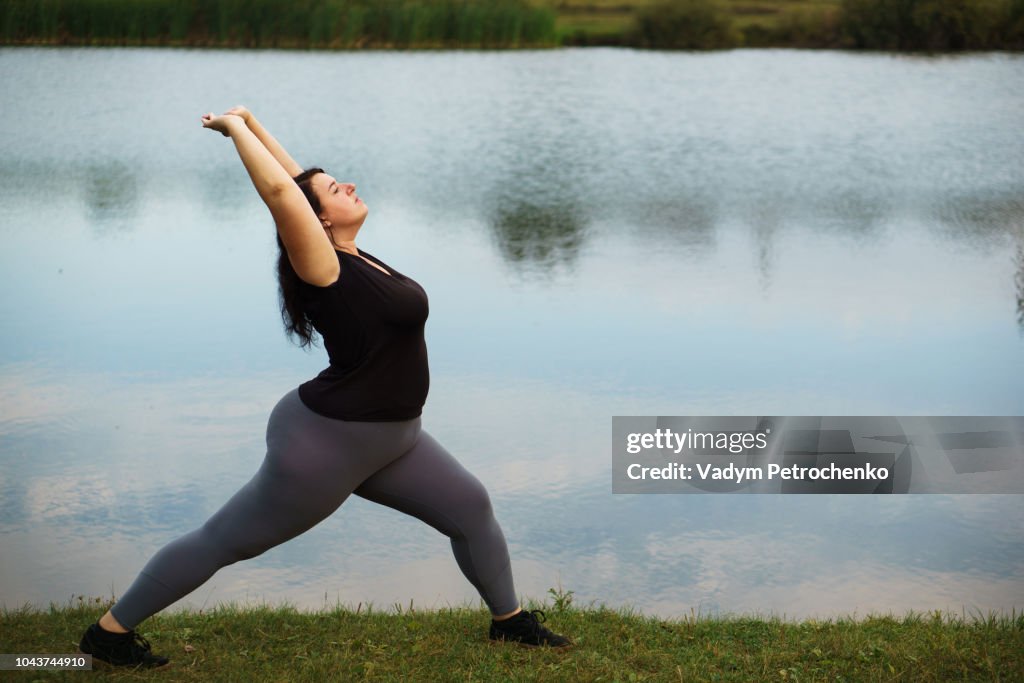 Overweight woman training near lake