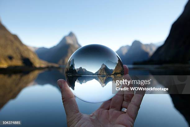 man holding crystal ball in landscape - reflection photos et images de collection