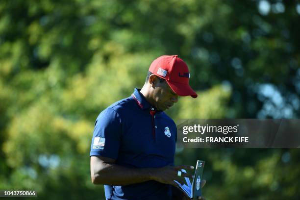 Golfer Tiger Woods looks at his notepad during his singles match with Europe's Spanish golfer Jon Rahm on the third day of the 42nd Ryder Cup at Le...