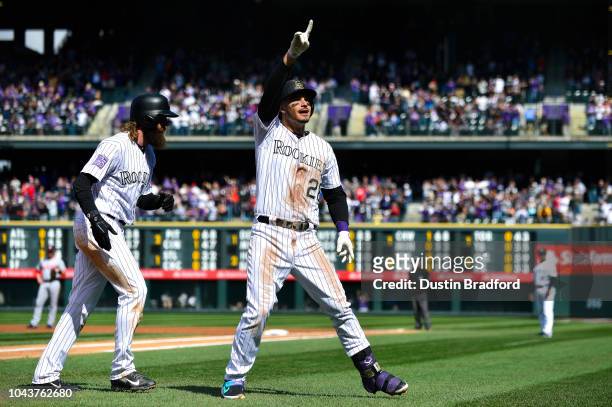 Nolan Arenado of the Colorado Rockies points to the crowd and is congratulated by Charlie Blackmon after hitting a first inning two-run homerun...