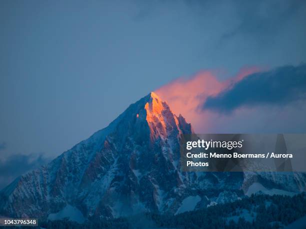 an early morning picture of the first sun rays setting the pyramid summit of the bietschhorn mountain on fire. - alpengloed stockfoto's en -beelden
