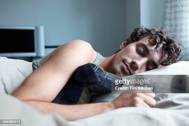 man sleeping in bed with stuffed animal - young man to bed photos et images de collection