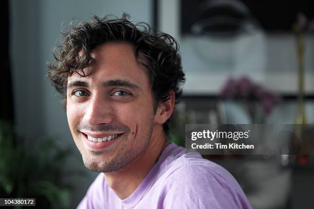 portrait of man in modern apartment, smiling - curly hair man stock pictures, royalty-free photos & images