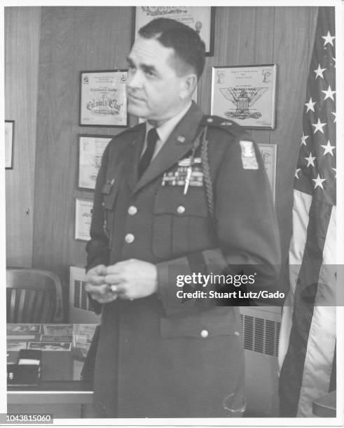 Black and white photograph of a dark-haired, United States Military Officer, shown standing, from the waist up, in three quarter profile view, with a...