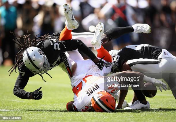 Carlos Hyde of the Cleveland Browns fumbles the ball after being hit by Reggie Nelson and Dominique Rodgers-Cromartie of the Oakland Raiders at...